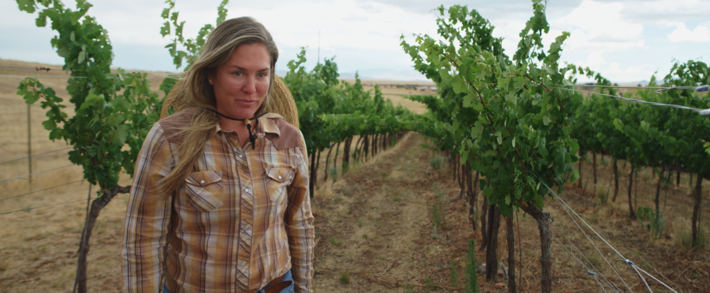 Picture of Brooke Ide of Vino Stache winery in front of grape vines.